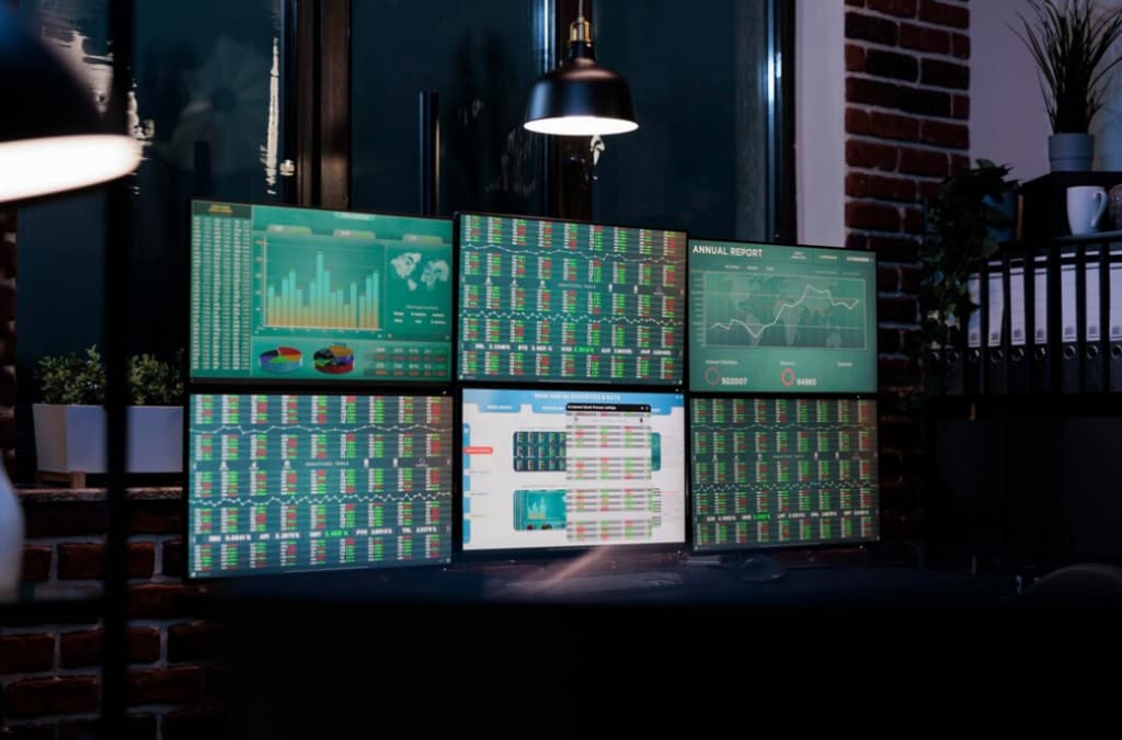 Multiple monitors on a desk displaying various financial charts and data