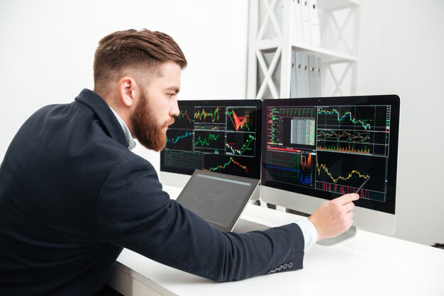 A man sits in front of a computer and analyzes a graph