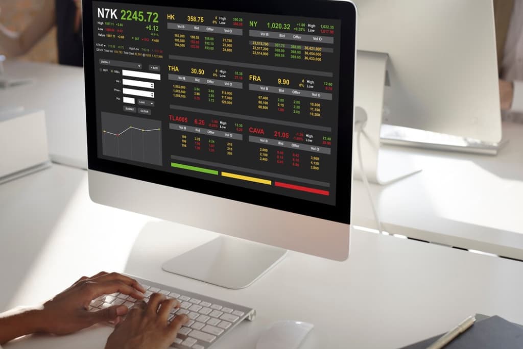 Hands typing on a keyboard with a stock market analysis display on the screen