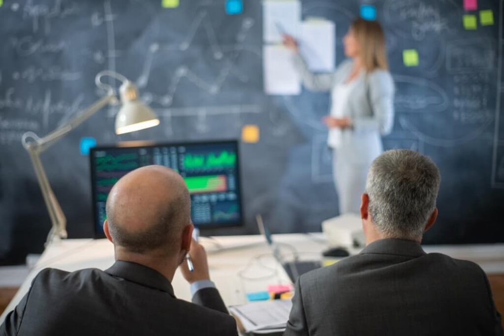 A presenter explains financial strategies to a businessman in an office